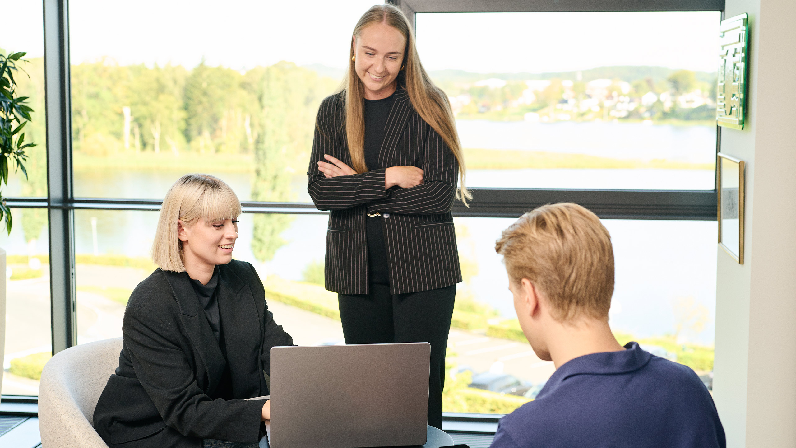To kvinder og en mand der holder møde ved en computer