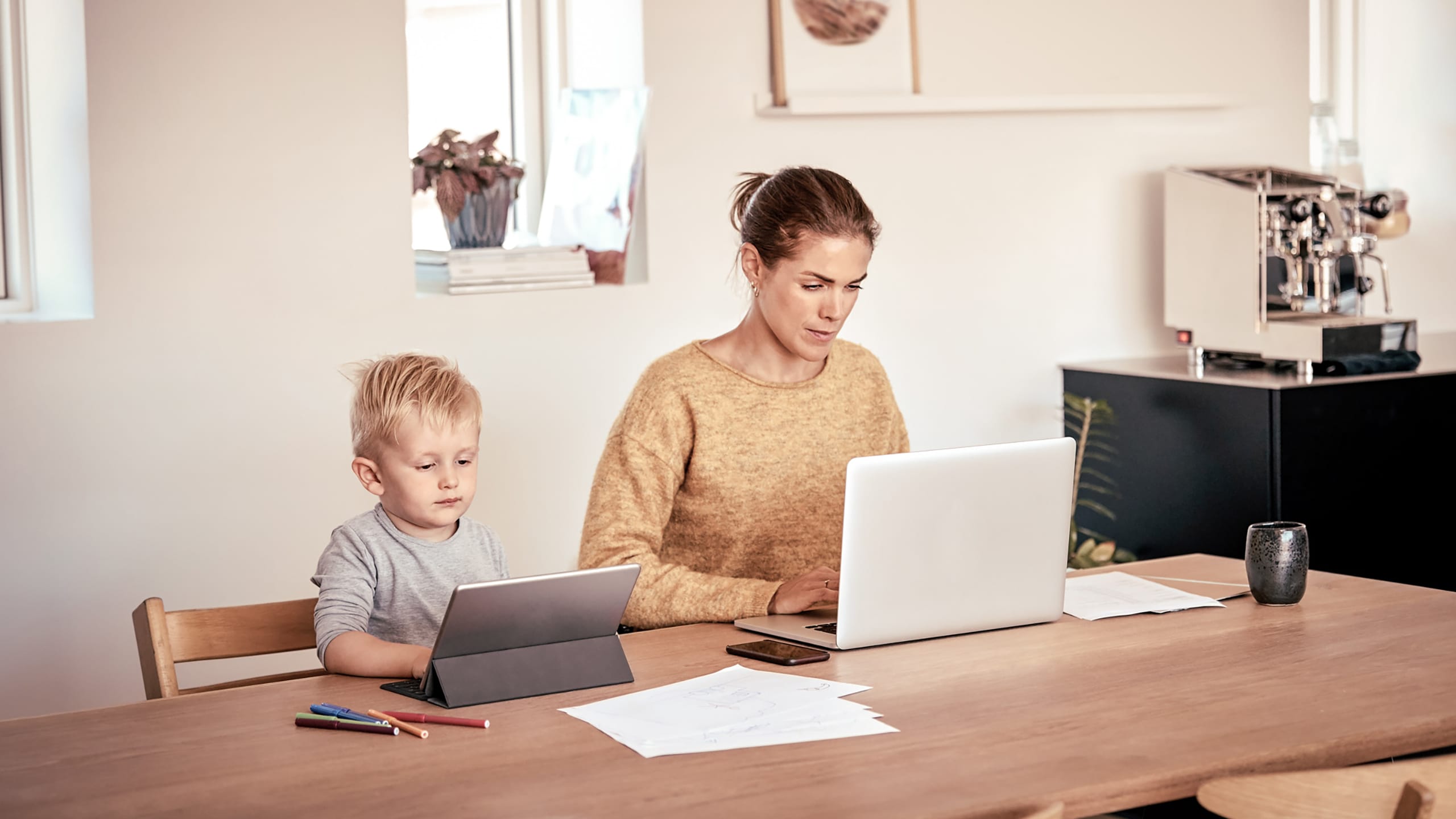 Mor og søn foran henholdsvis laptop og tablet