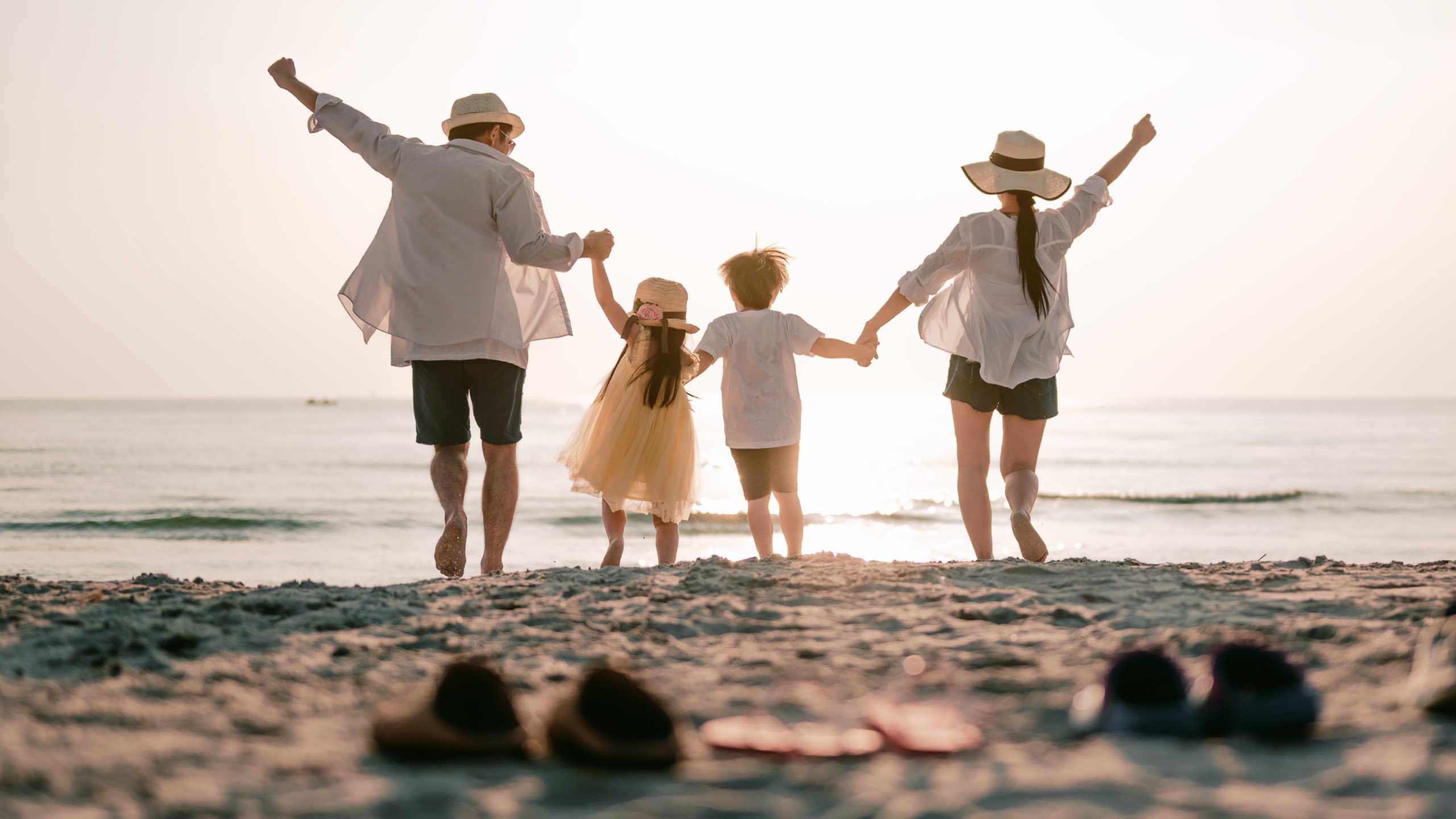 Familie med hænderne over hovedet på strand