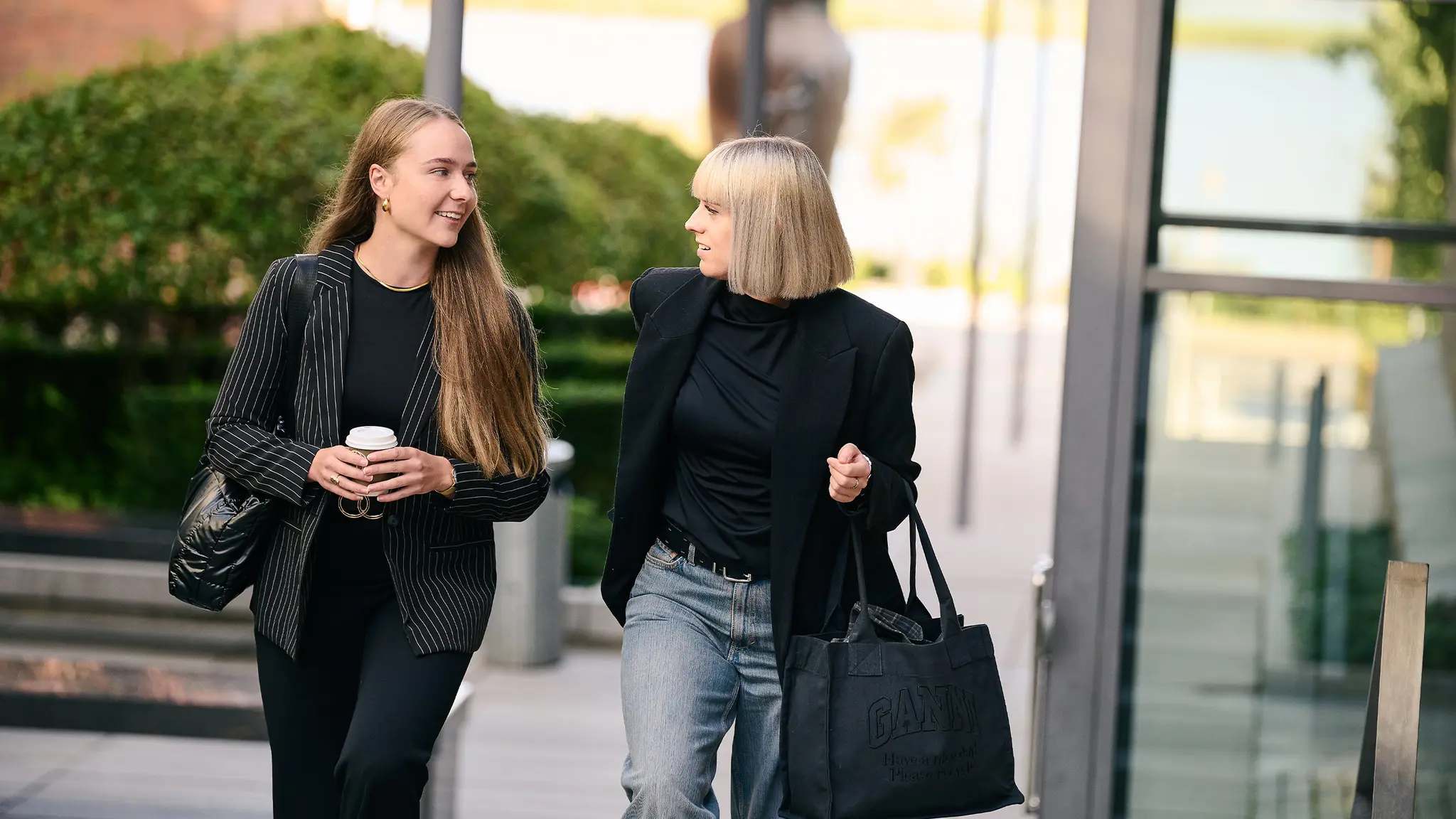 To kvinder med kaffe og tasker går tur i byen