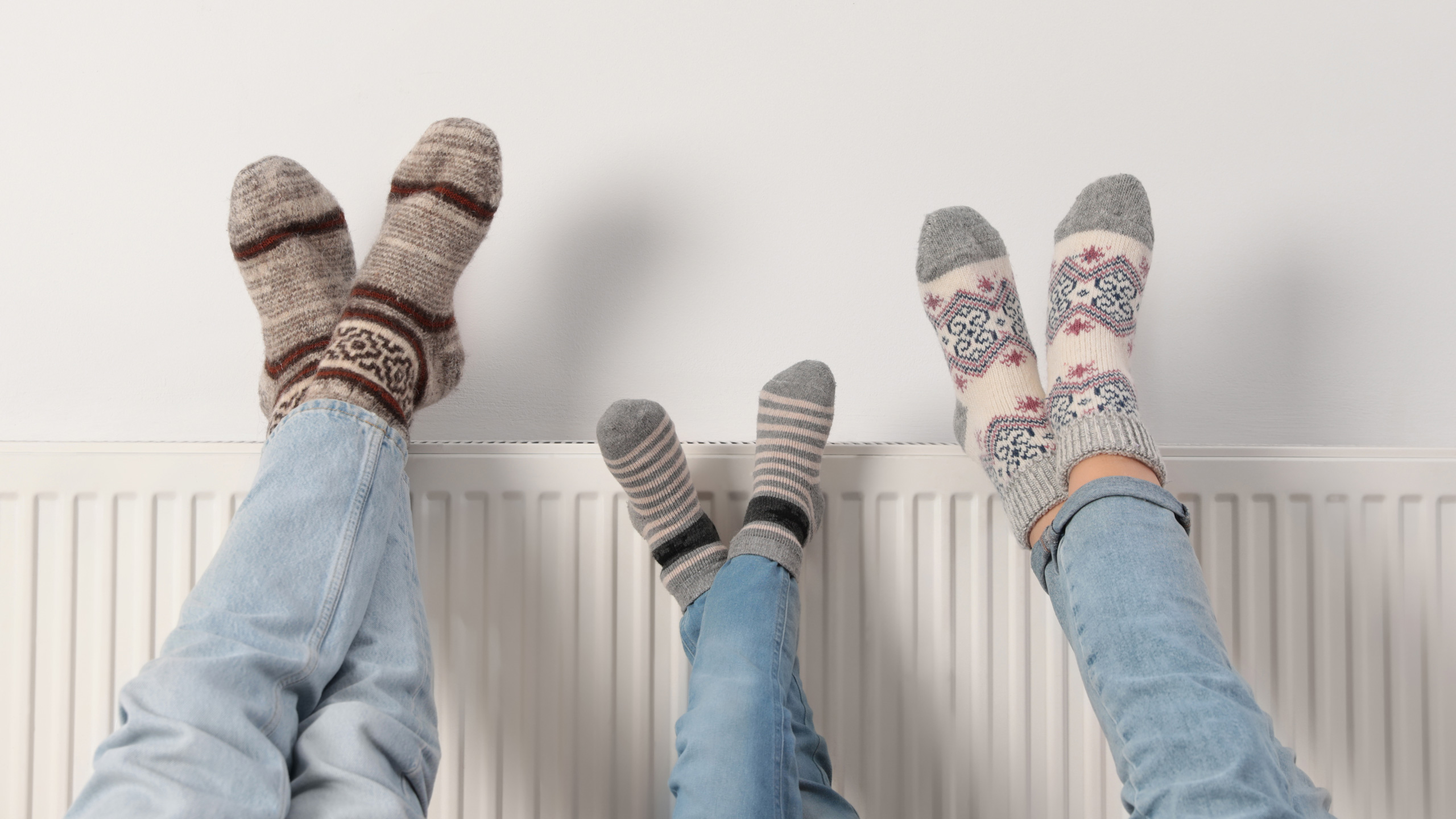 Tre ben med striksokker på op af radiator