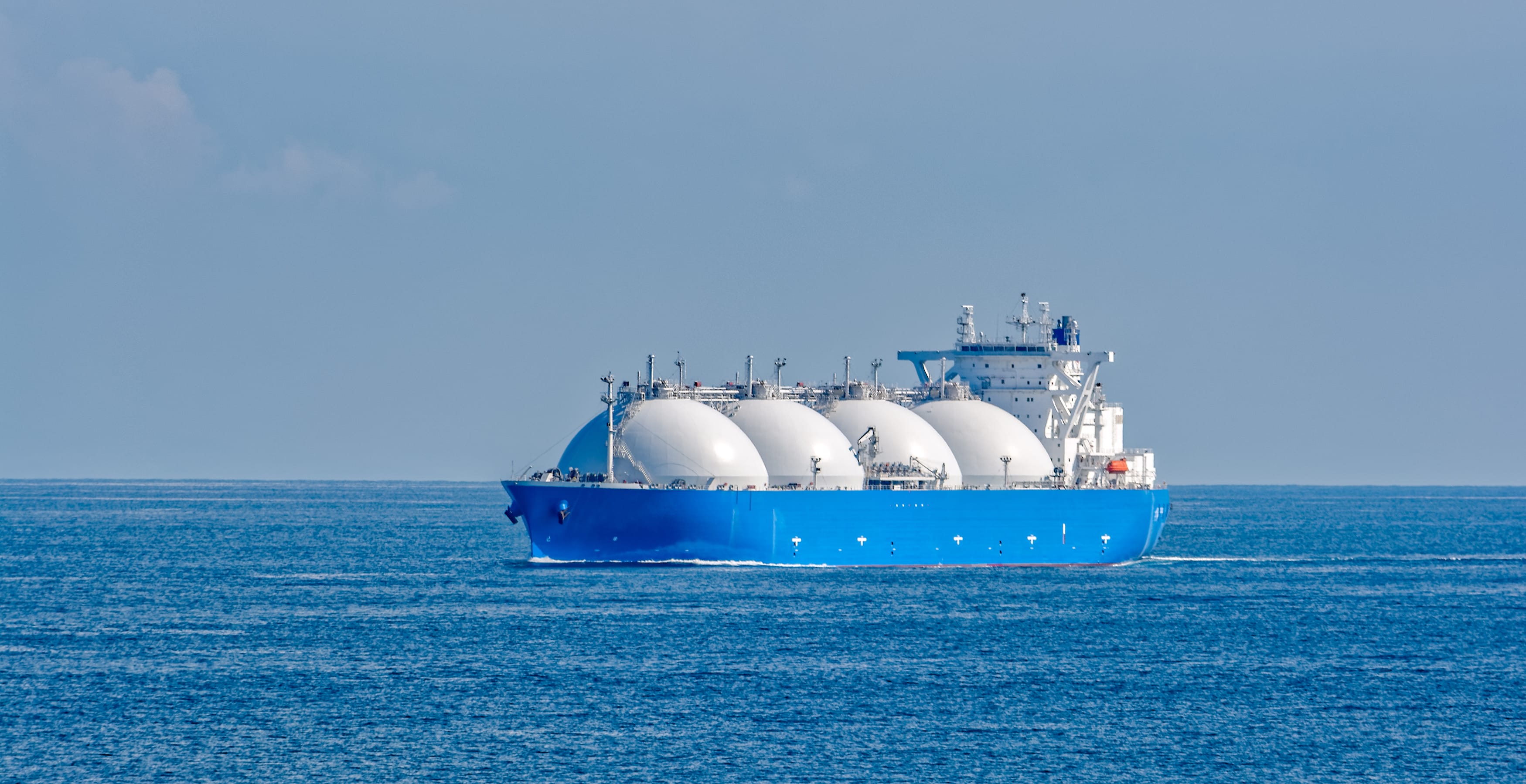 LNG-tankskib set på afstand på et åbent hav med blå himmel