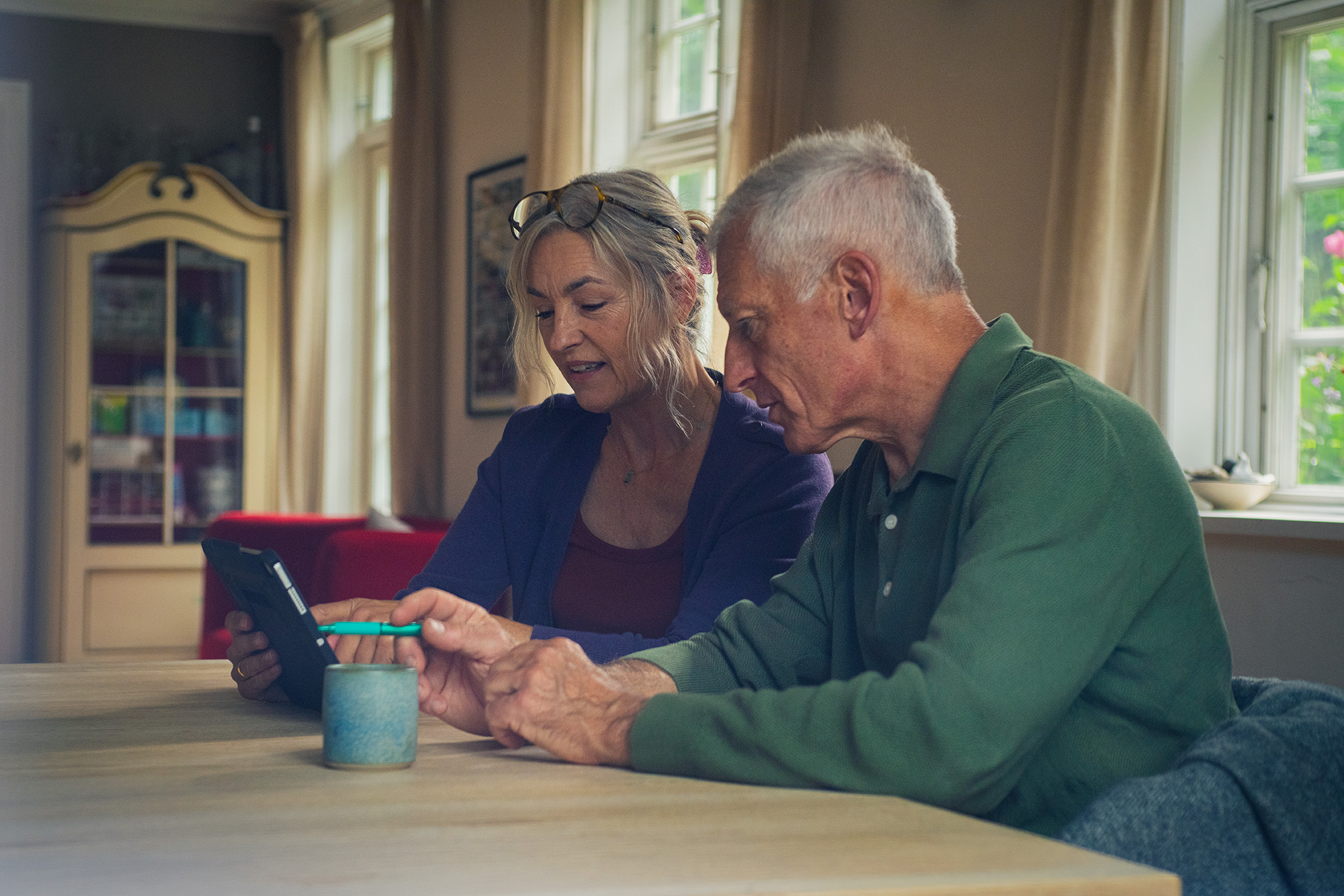 Mand og kvinde studerer tablet mens de sidder ved et spisebord