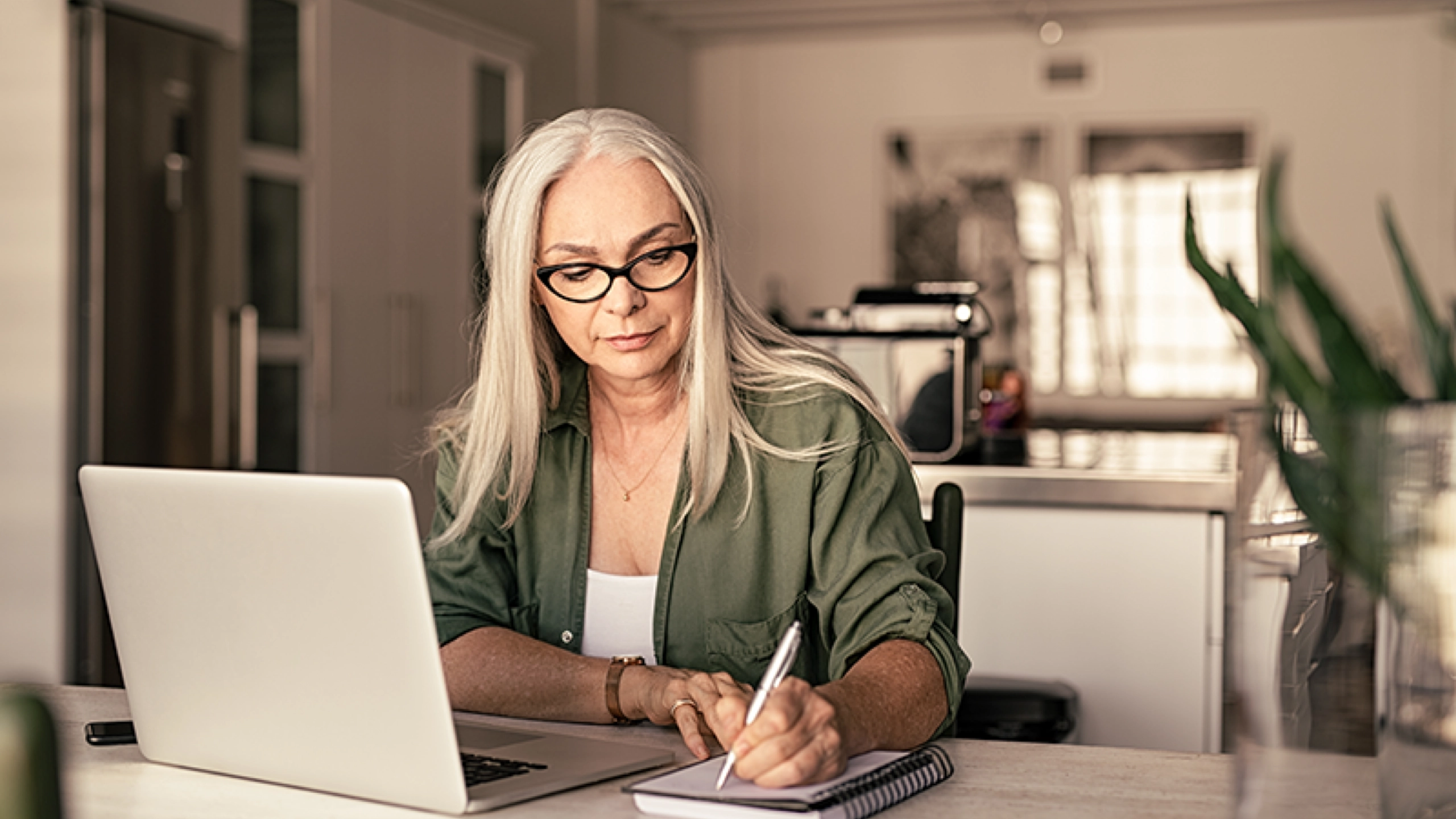 Kvinde med laptop skriver på en blok