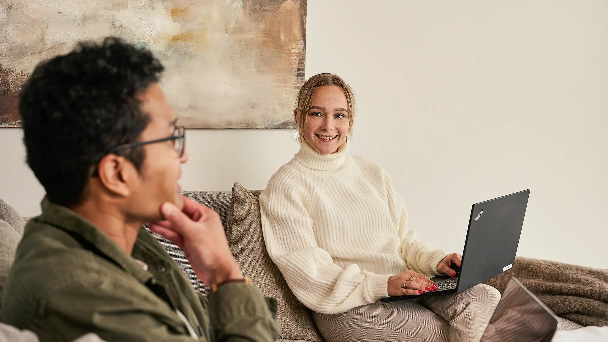 Kvinde og mand sidder med computer i sofa