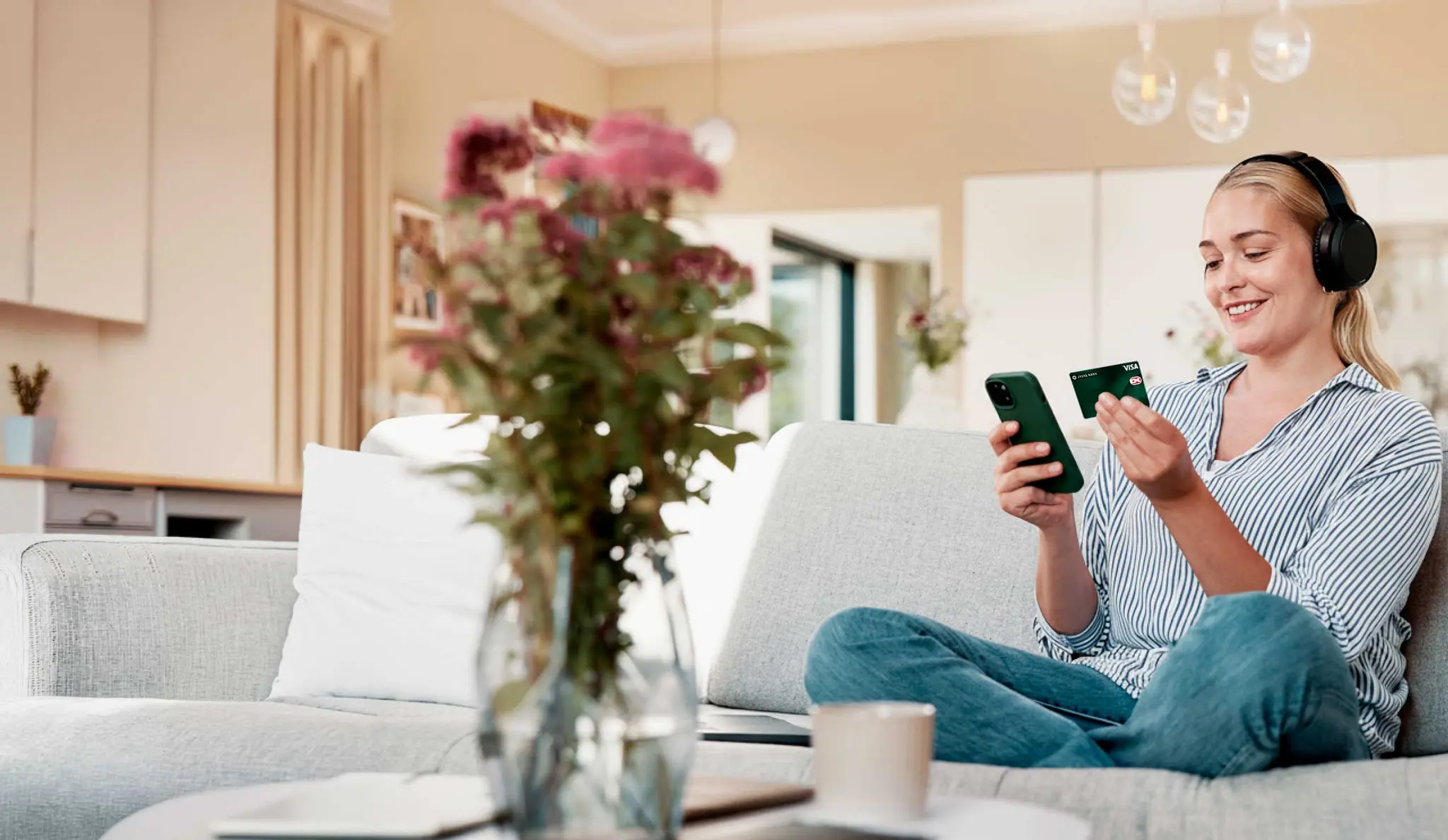 Kvinde i sofa shopper online med mobil og betalingskort