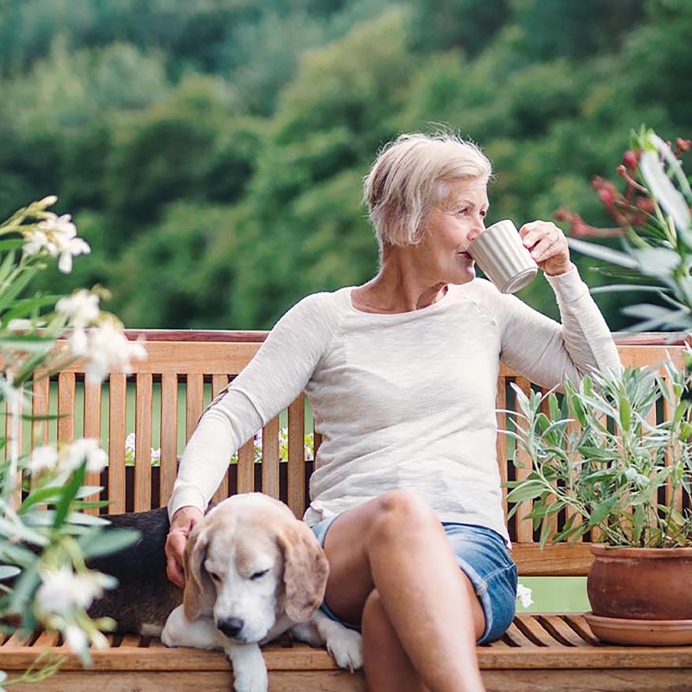 Kvinde i have med hund på bænk