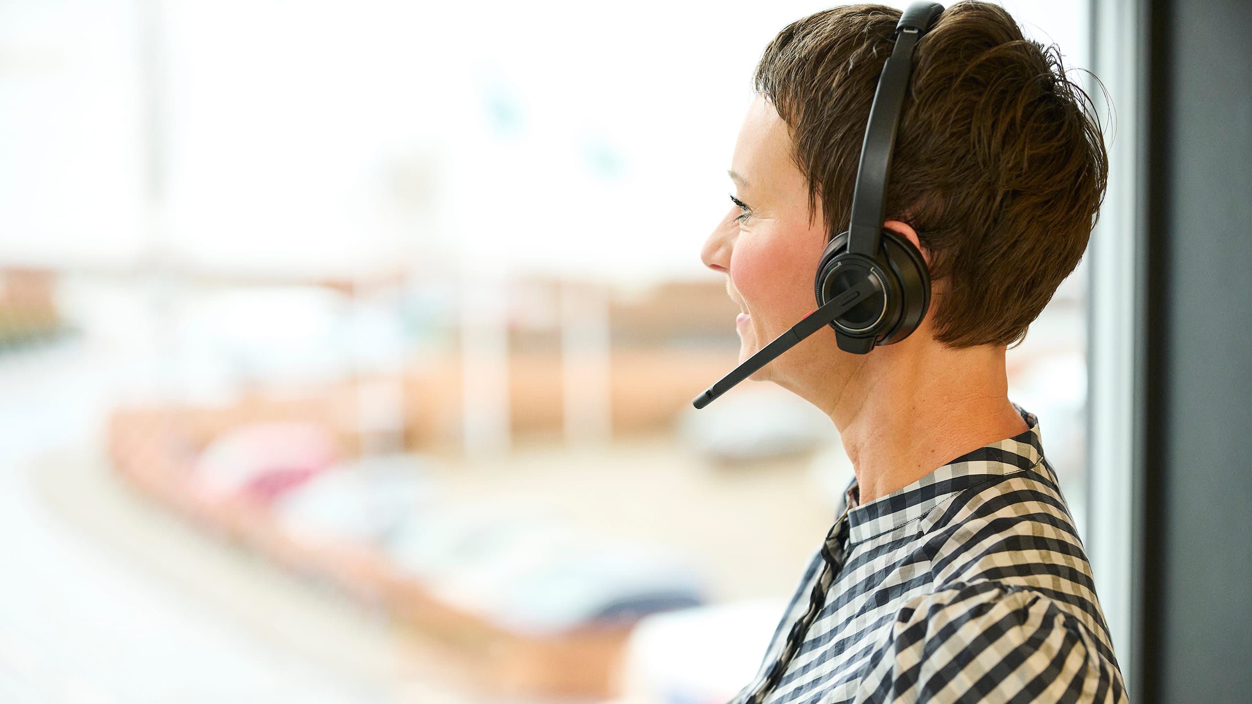 Kvinde med headset kigger ud af et vindue