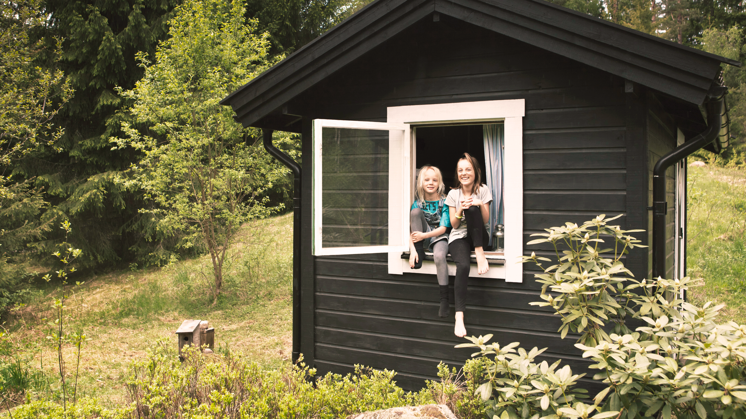 To børn i et vindue i et lille anneks eller legehus