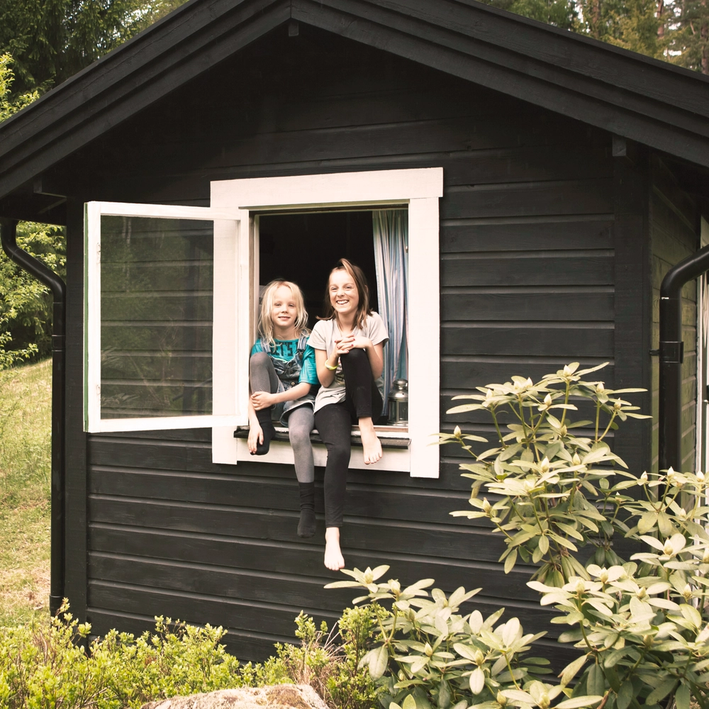 To børn i et vindue i et lille anneks eller legehus