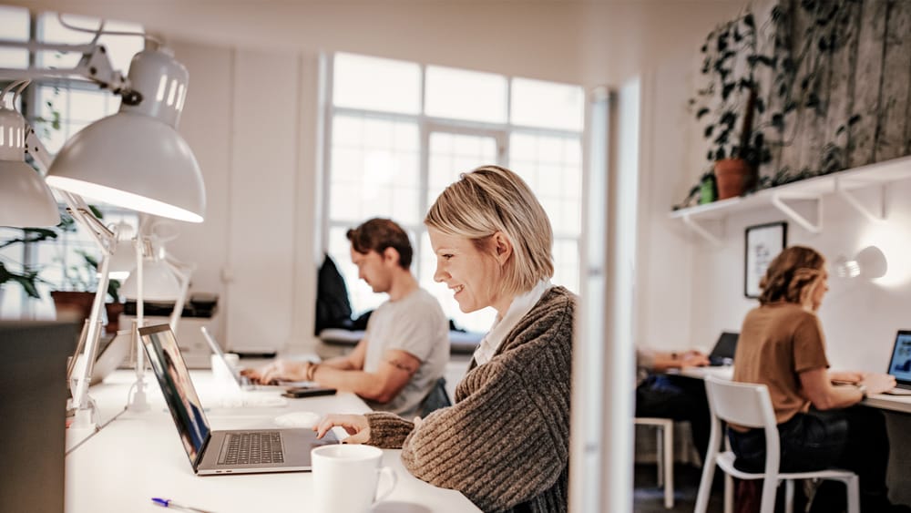 Kvinde med laptop i åbent kontormiljø