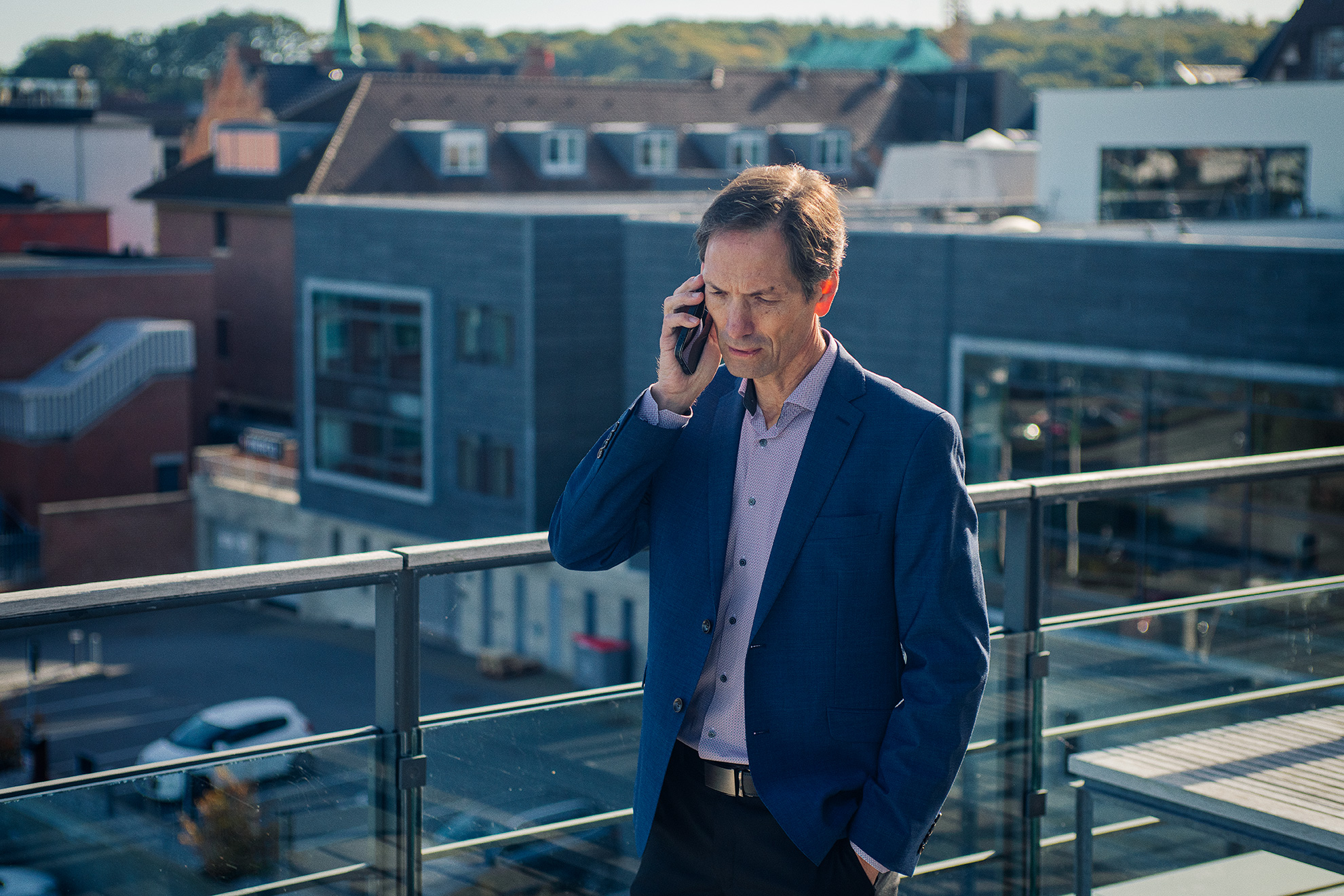 Mand med mobil ved øret, taler på højtliggende terrasse