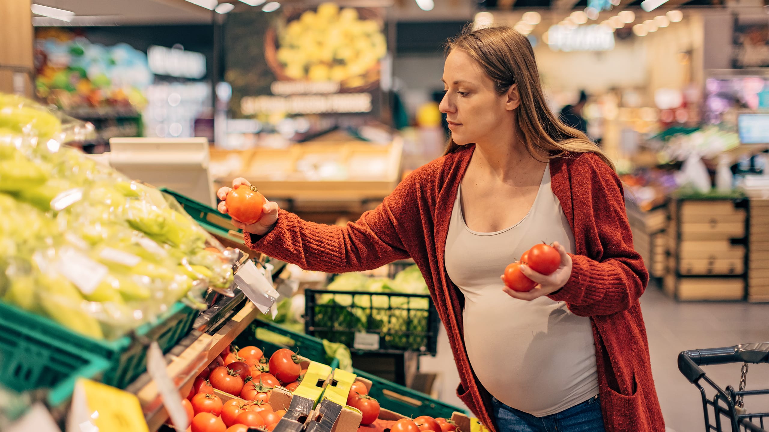 Gravid kvinde ved frugt i supermarked