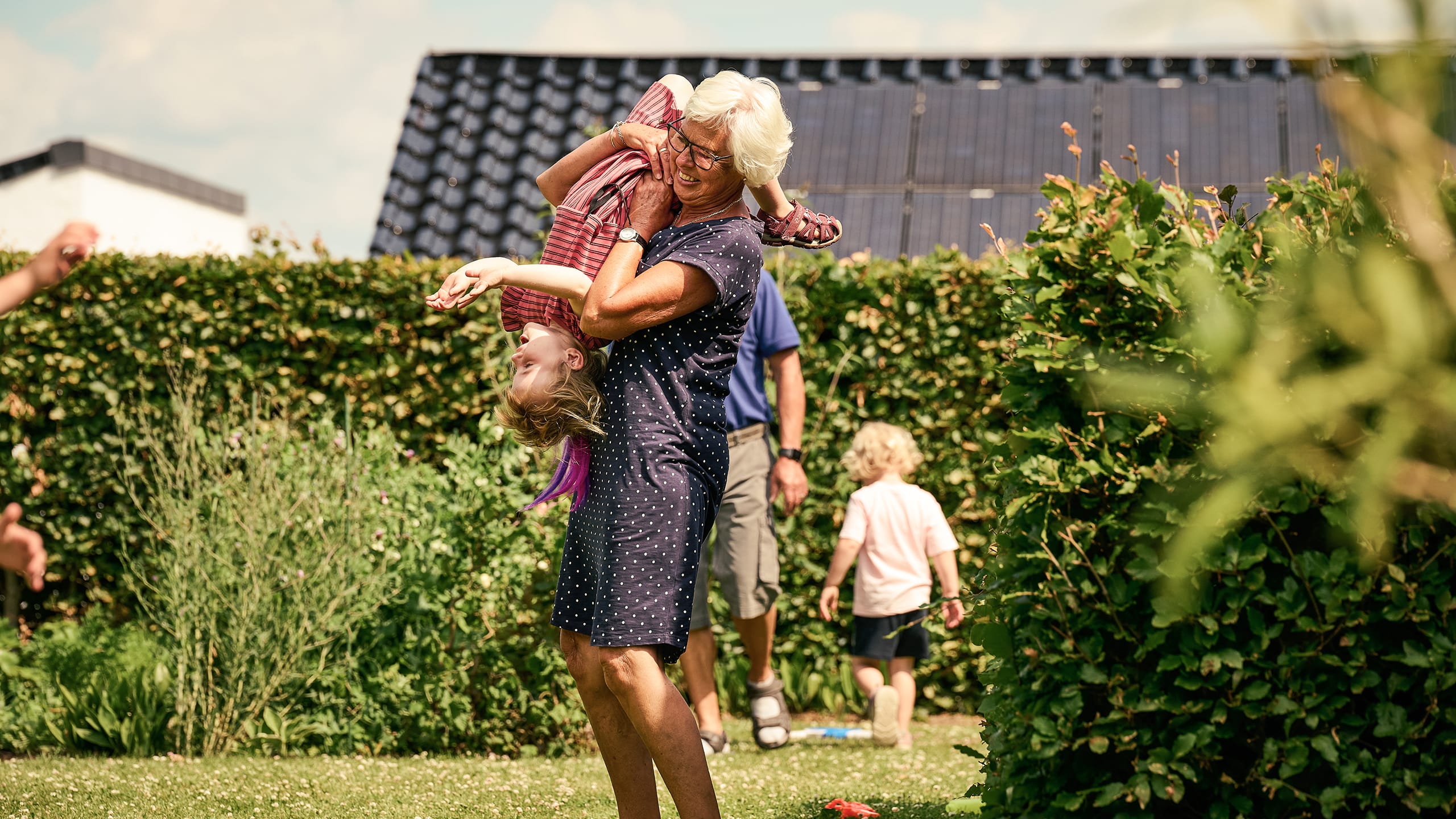 Bedstemor løfter barnebarn, så det vender på hovedet i haven