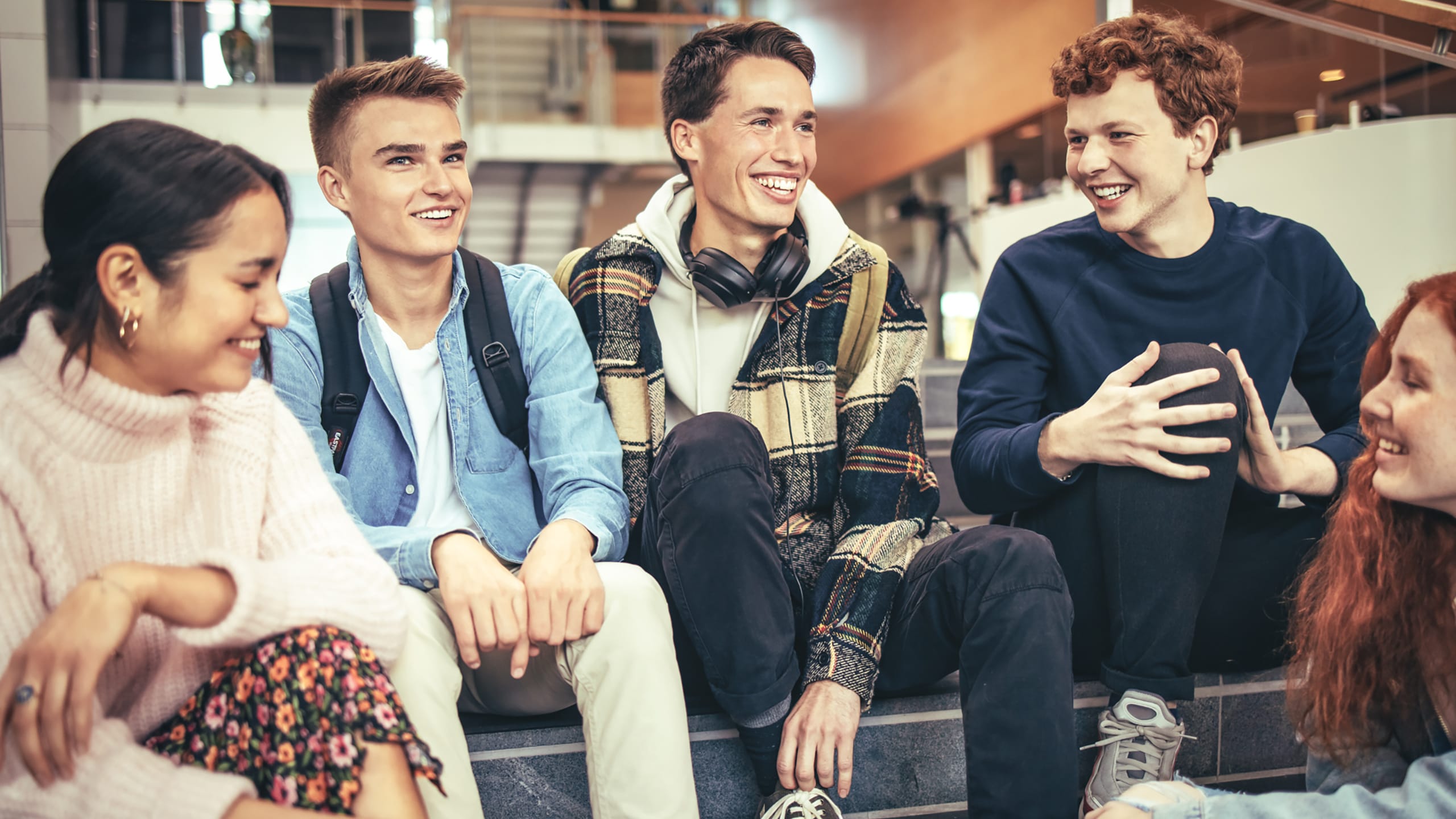 5 unge drenge og piger sidder på trappe