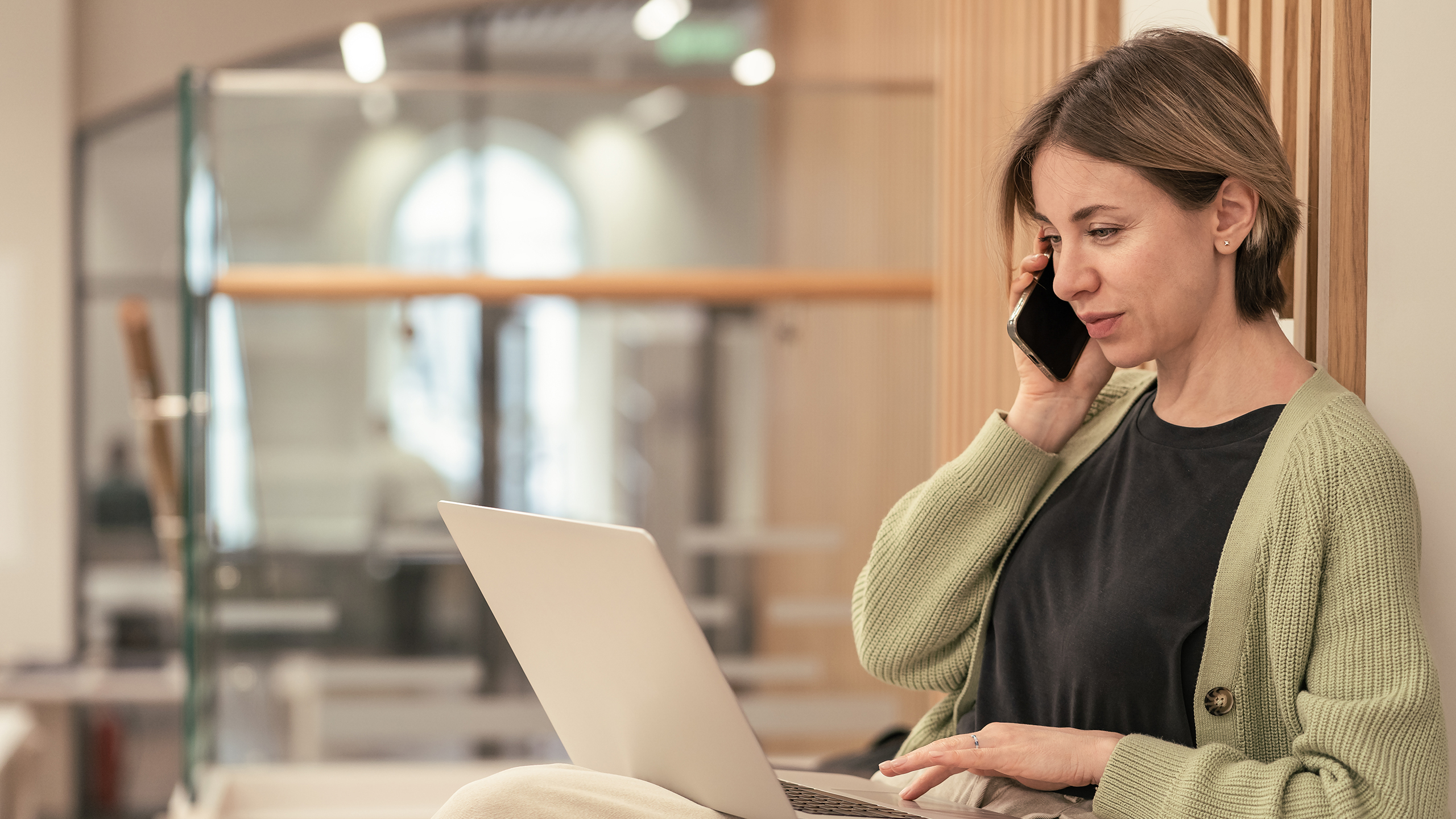 Kvinde ved computer og med telefon ved øret