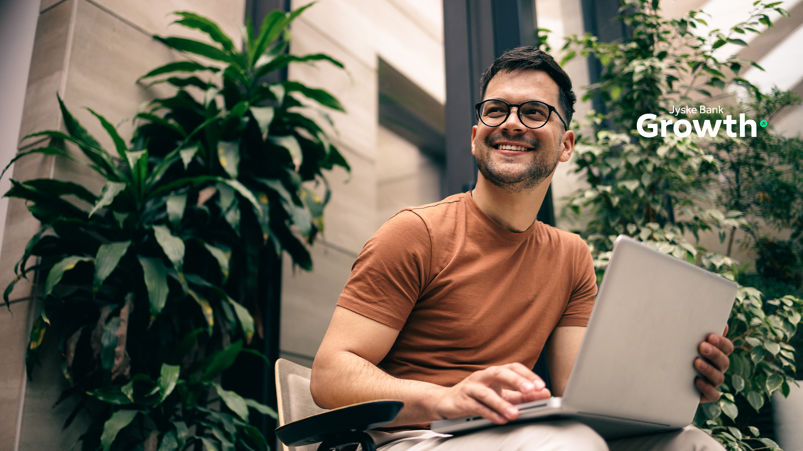 Smilende mand med computer og planter