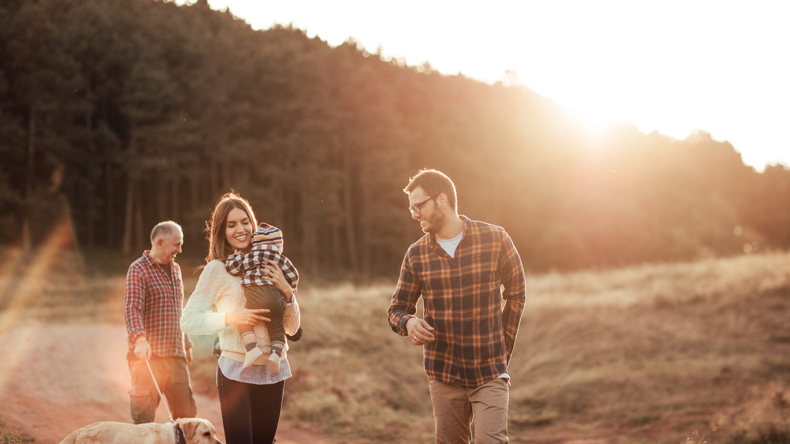 Tre generationer plus hund går tur i skoven