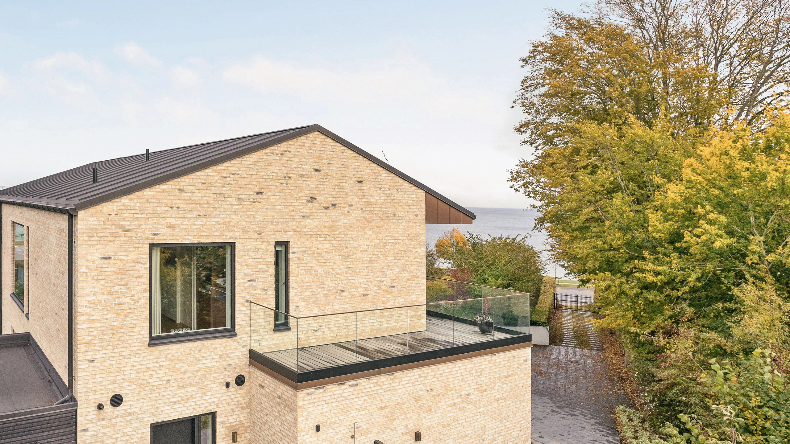Hus i to plan - med terrasse - bygget af gule mursten og med sort tag