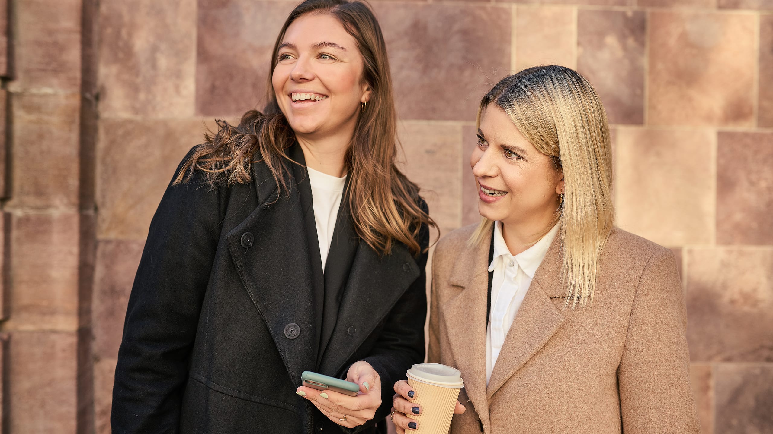 To kvinder med kaffe og mobil