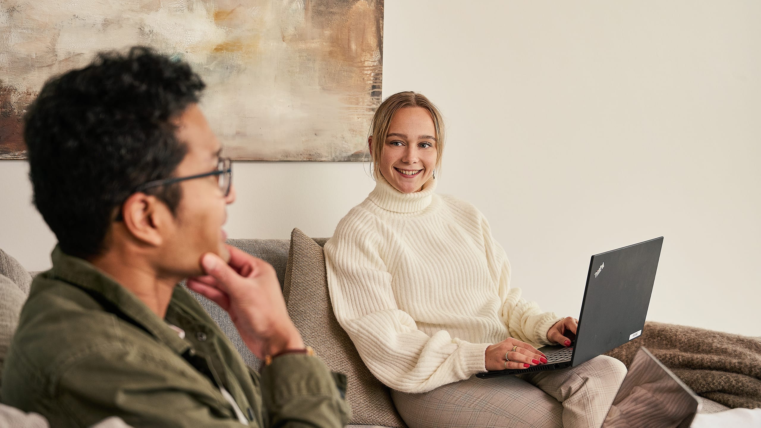 Kvinde og mand sidder med computer i sofa