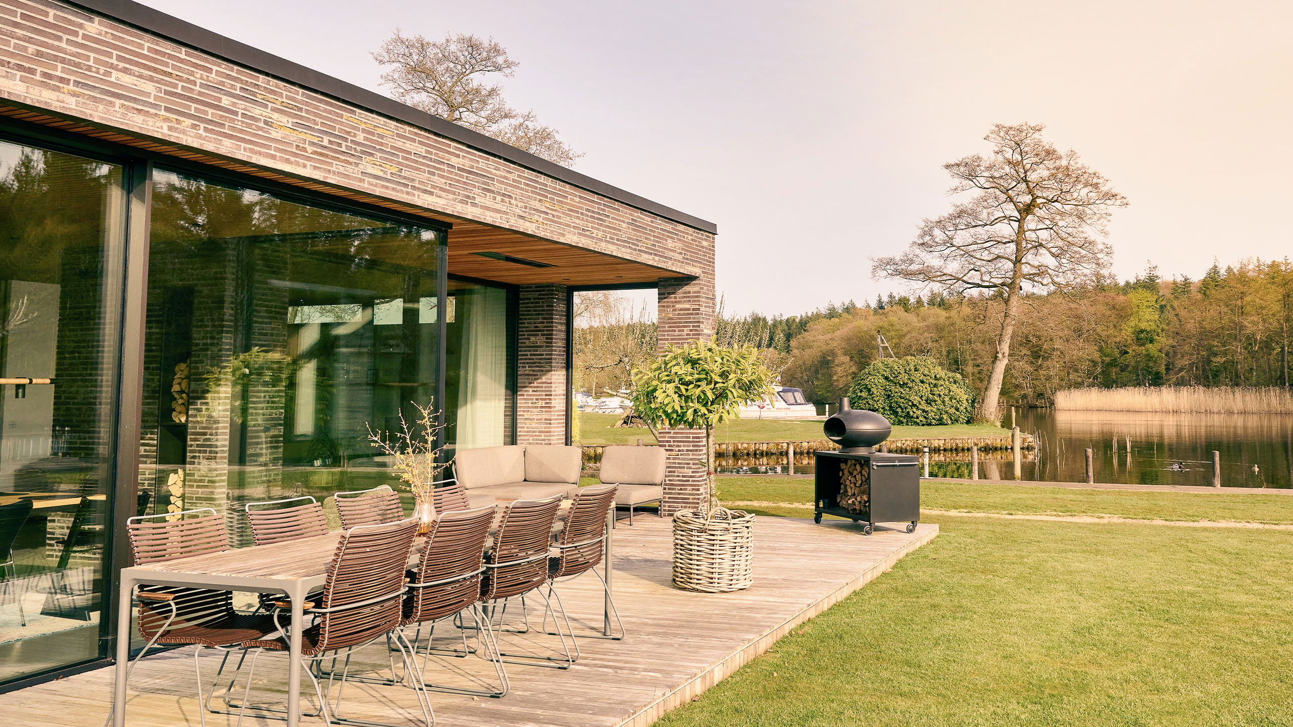 Terrasse ved sø med havemøbler, kurv og brændeovn
