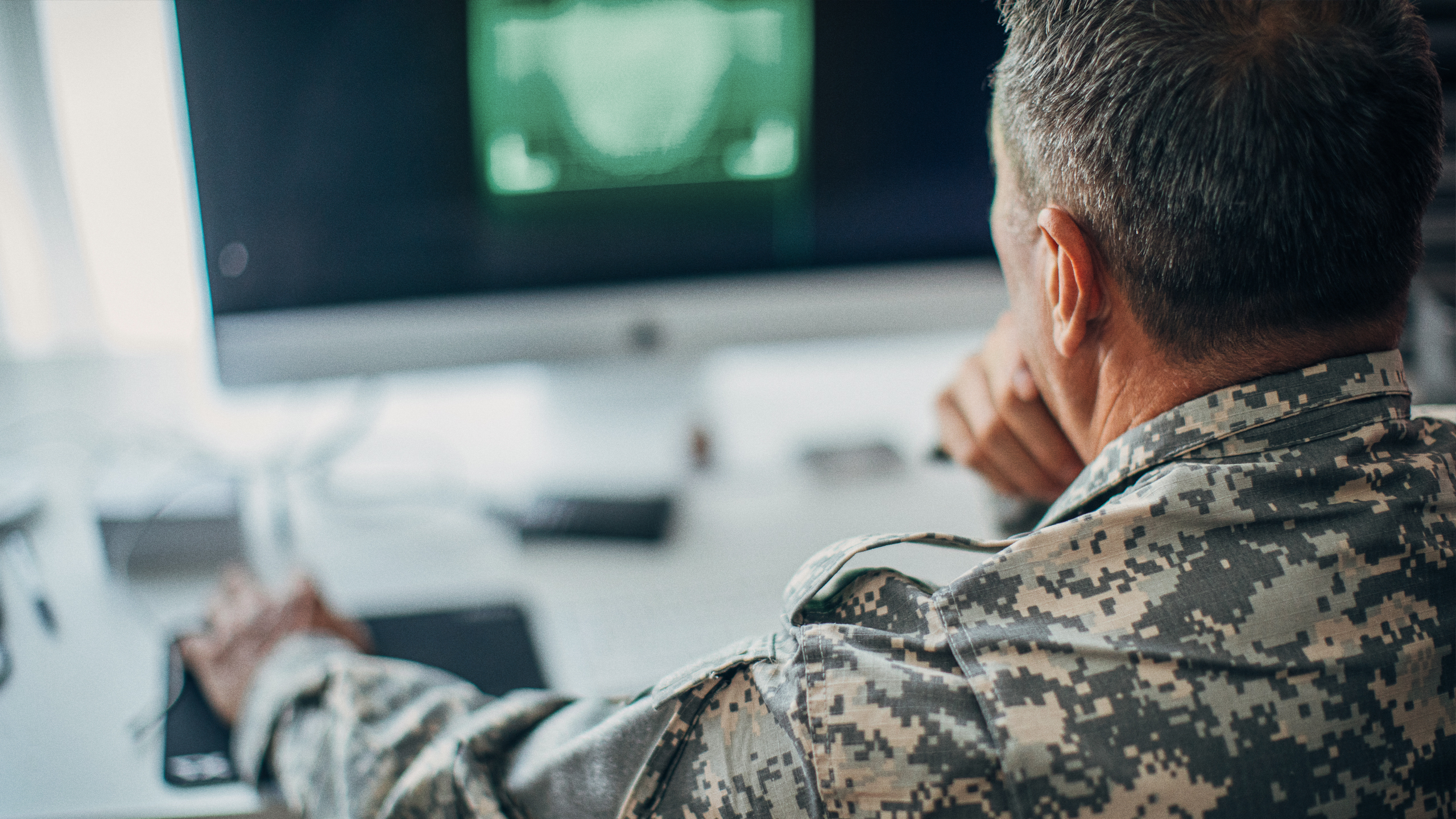 Ryggen af soldat, der sidder ved computer
